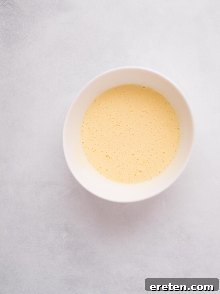 A single beaten egg in a shallow bowl, ready for the breading process.