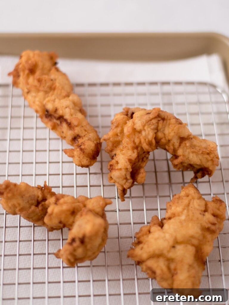 Freshly fried boneless wings resting on a cooling rack, allowing excess oil to drain and maintaining crispiness.