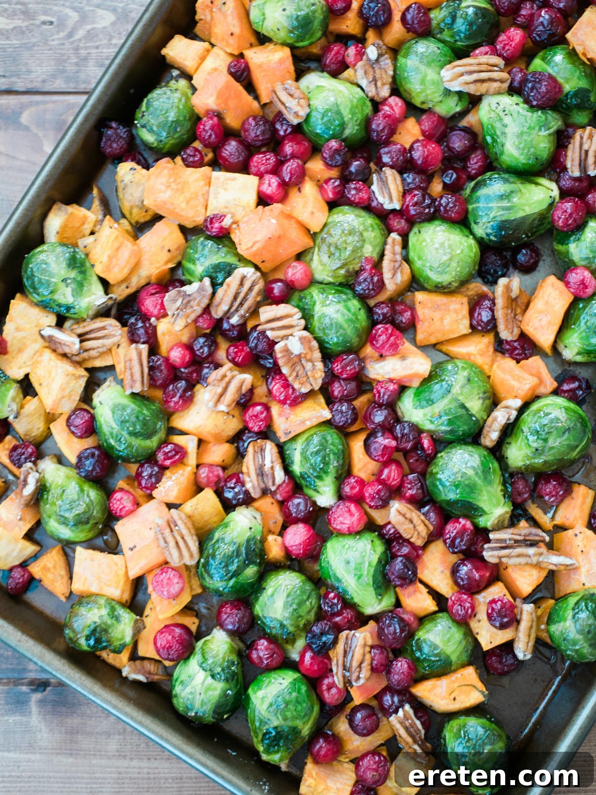Close-up of roasted butternut squash and Brussels sprouts with cranberries and pecans, drizzled with honey, showcasing the rich texture and appealing glaze.