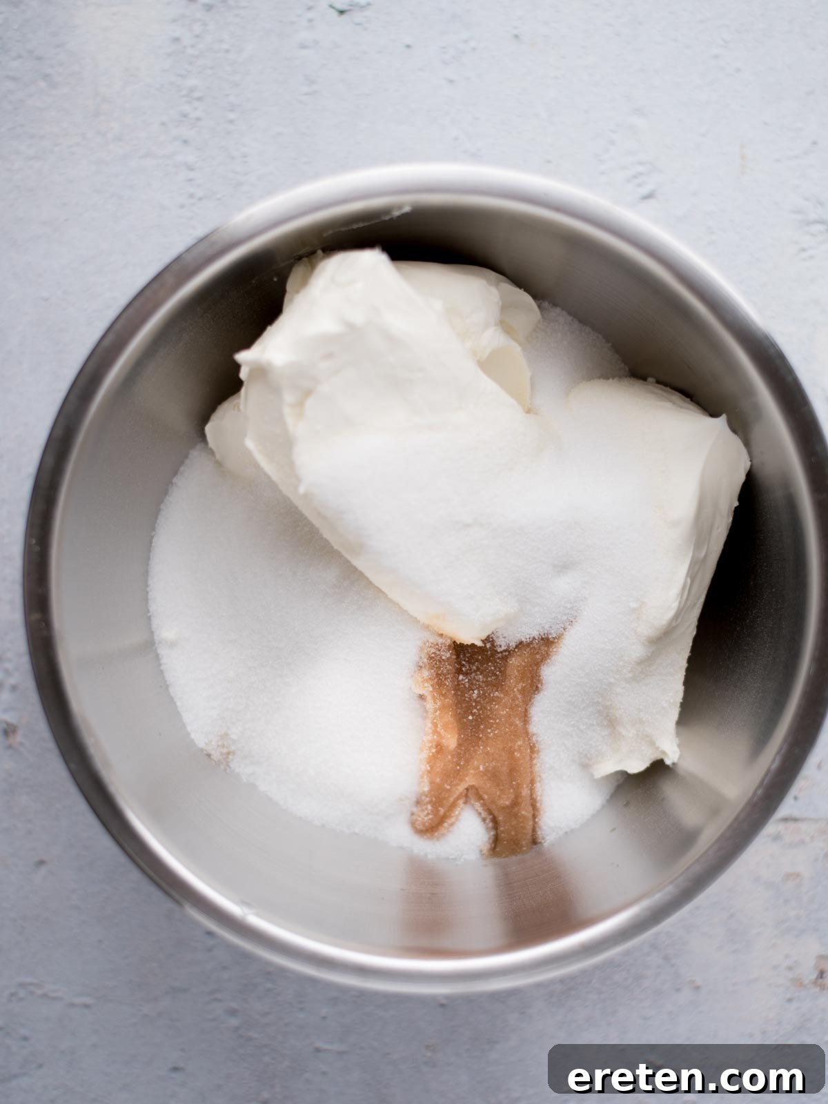 Cheesecake filling ingredients, including softened cream cheese, sugar, and vanilla, in a large mixing bowl.