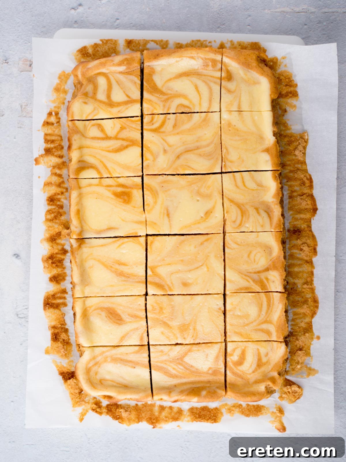 Neatly cut pumpkin cheesecake bars resting on parchment paper, ready to be served.