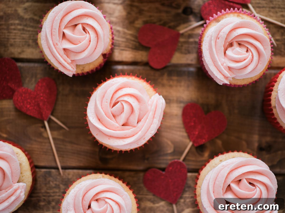 Delightful strawberry vanilla cupcakes with vibrant red liners and charming heart toppers, perfect for a special treat.