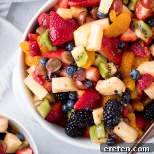 fruit salad with dressing in a while bowl with a serving spoon and a kitchen linen