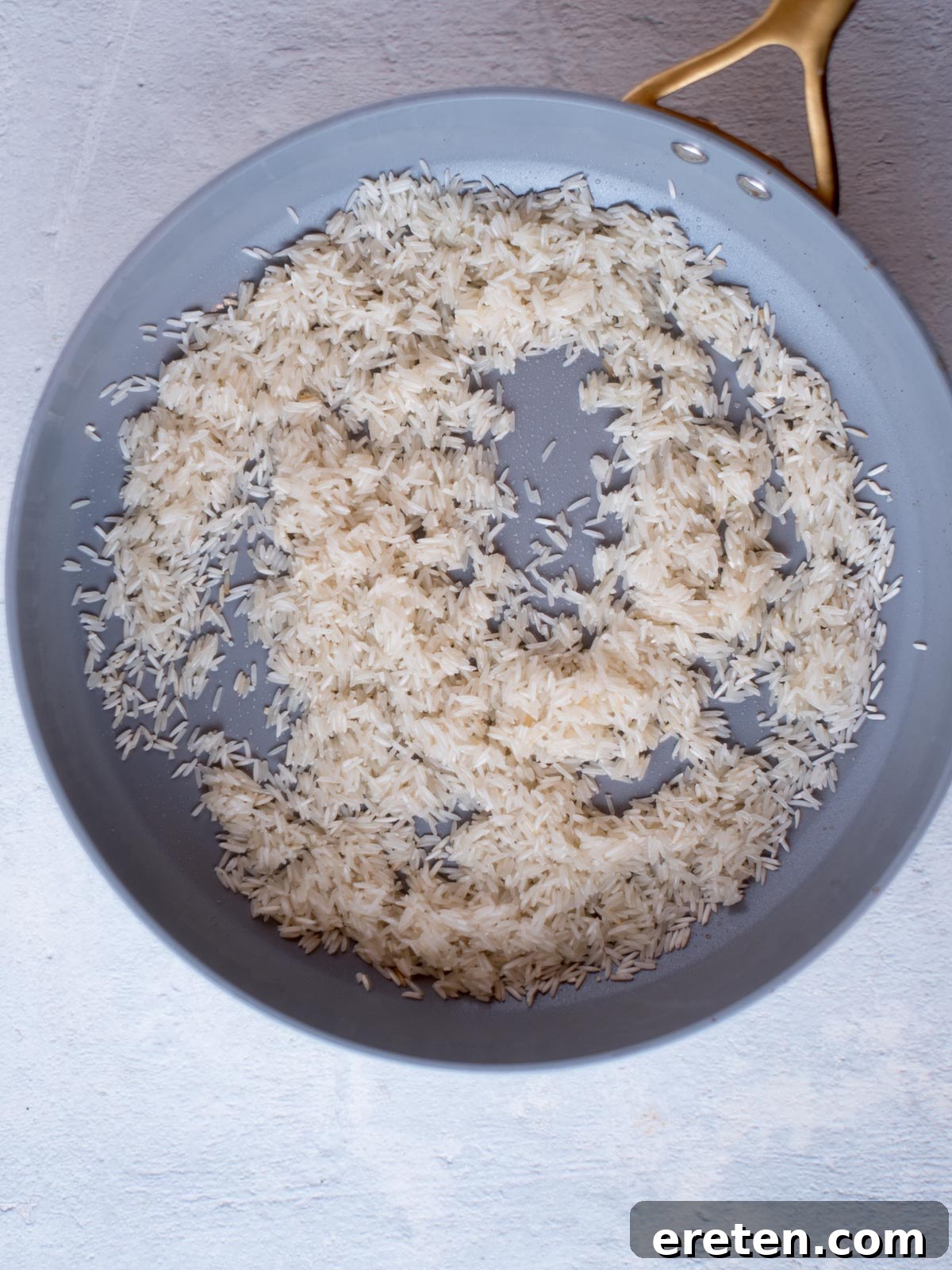 White rice being toasted in a stainless steel skillet with melted butter, salt, and lime juice, releasing its fragrant aroma.