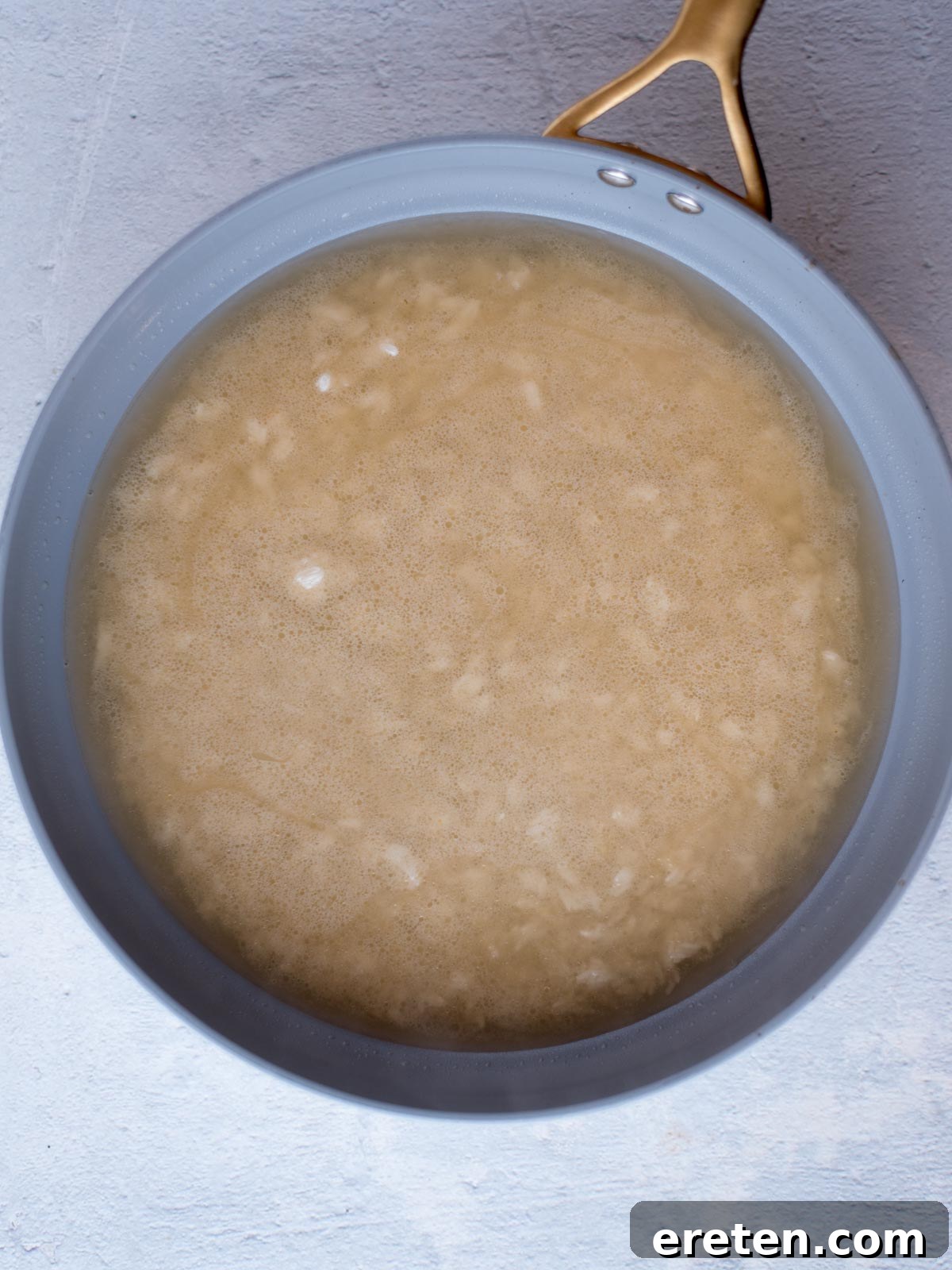 Chicken broth being poured into a skillet with toasted rice and lime juice, preparing for the simmering process.