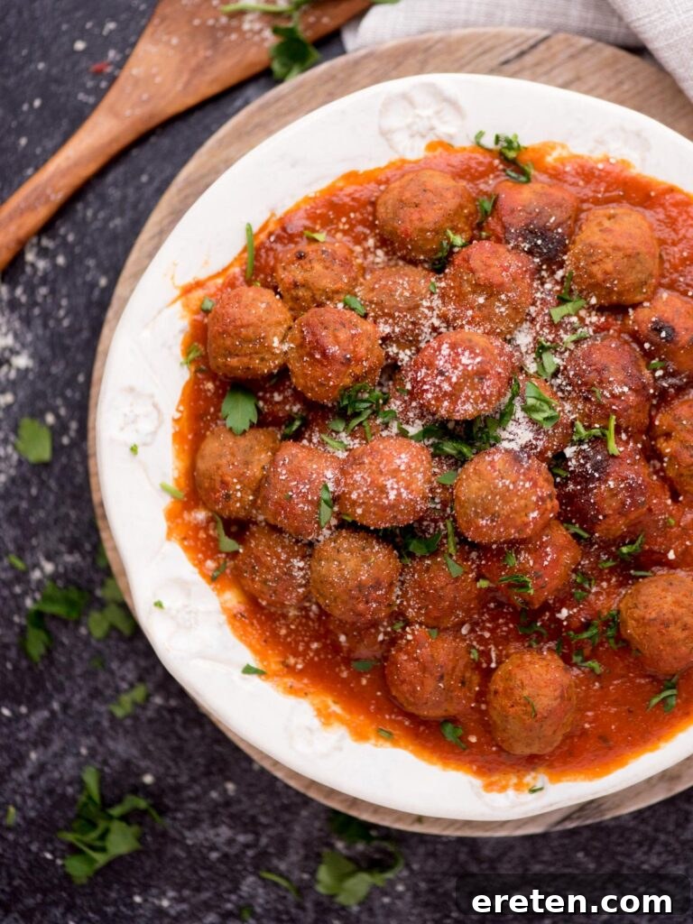 Pressure Cooker Frozen Meatballs 7 Top view of a bowl of meatballs and tomato sauce with a wooden spoon laying next to it, invitingly served.