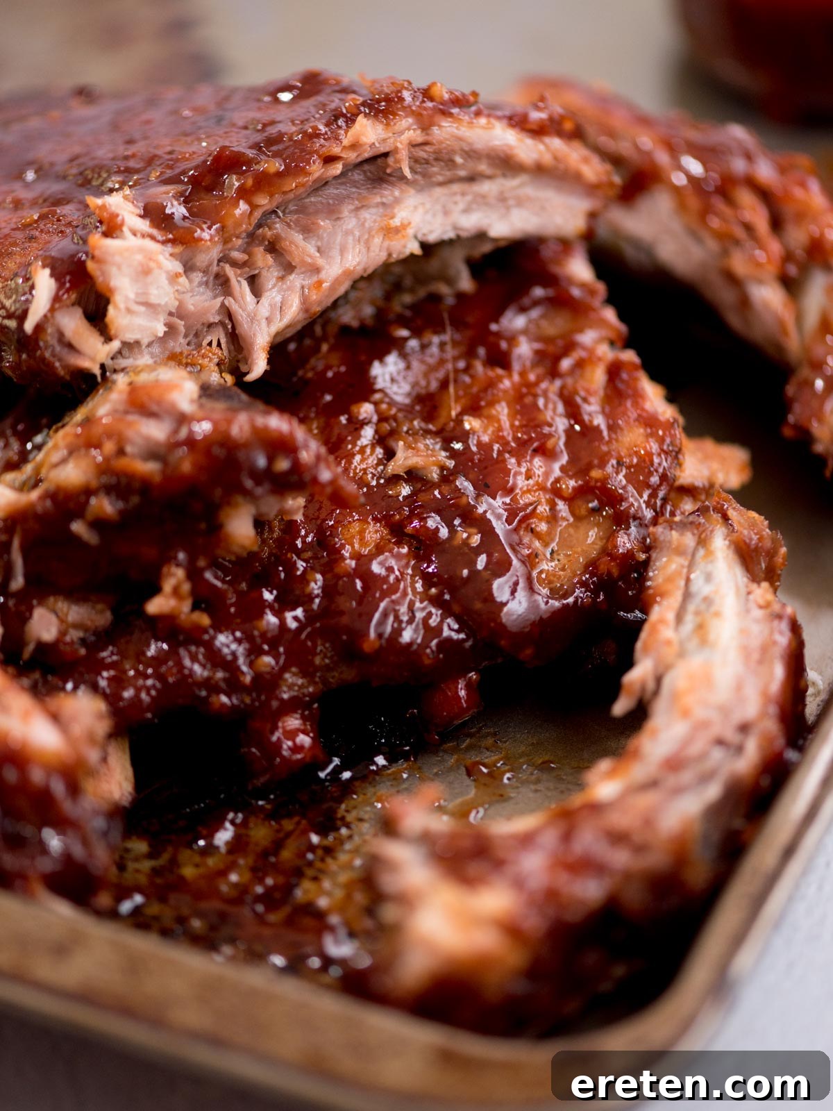 Close-up of a serving of tender, sauced ribs on a plate.