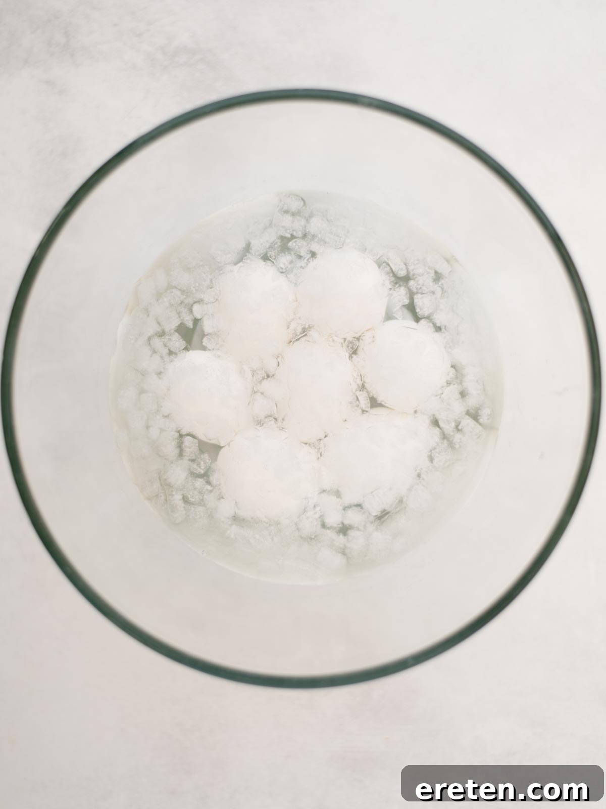 Peeled hard-boiled eggs chilling in a container in the refrigerator.