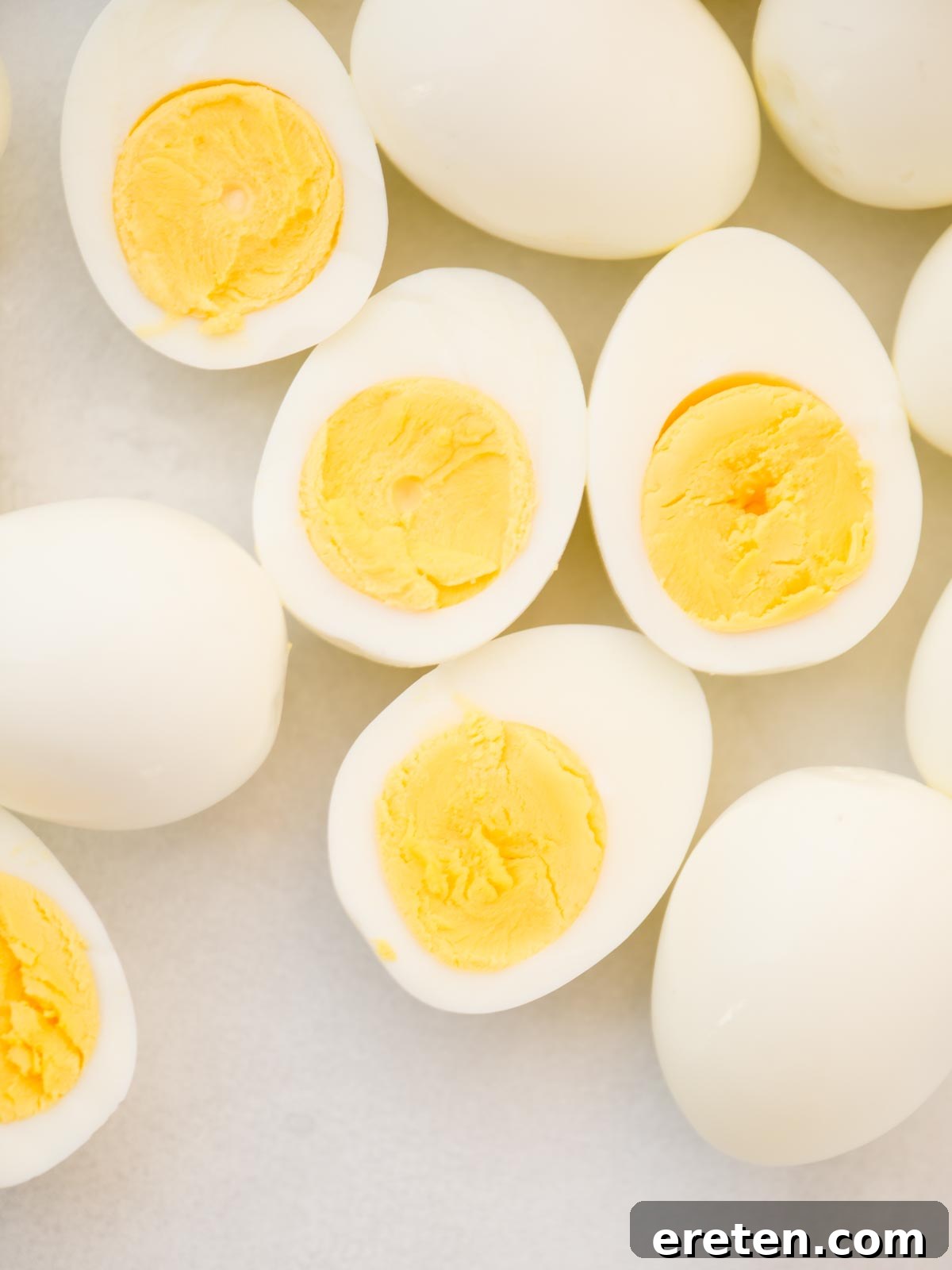 Egg yolks in a mixing bowl with mustard, salt, pepper, and mayonnaise being added.