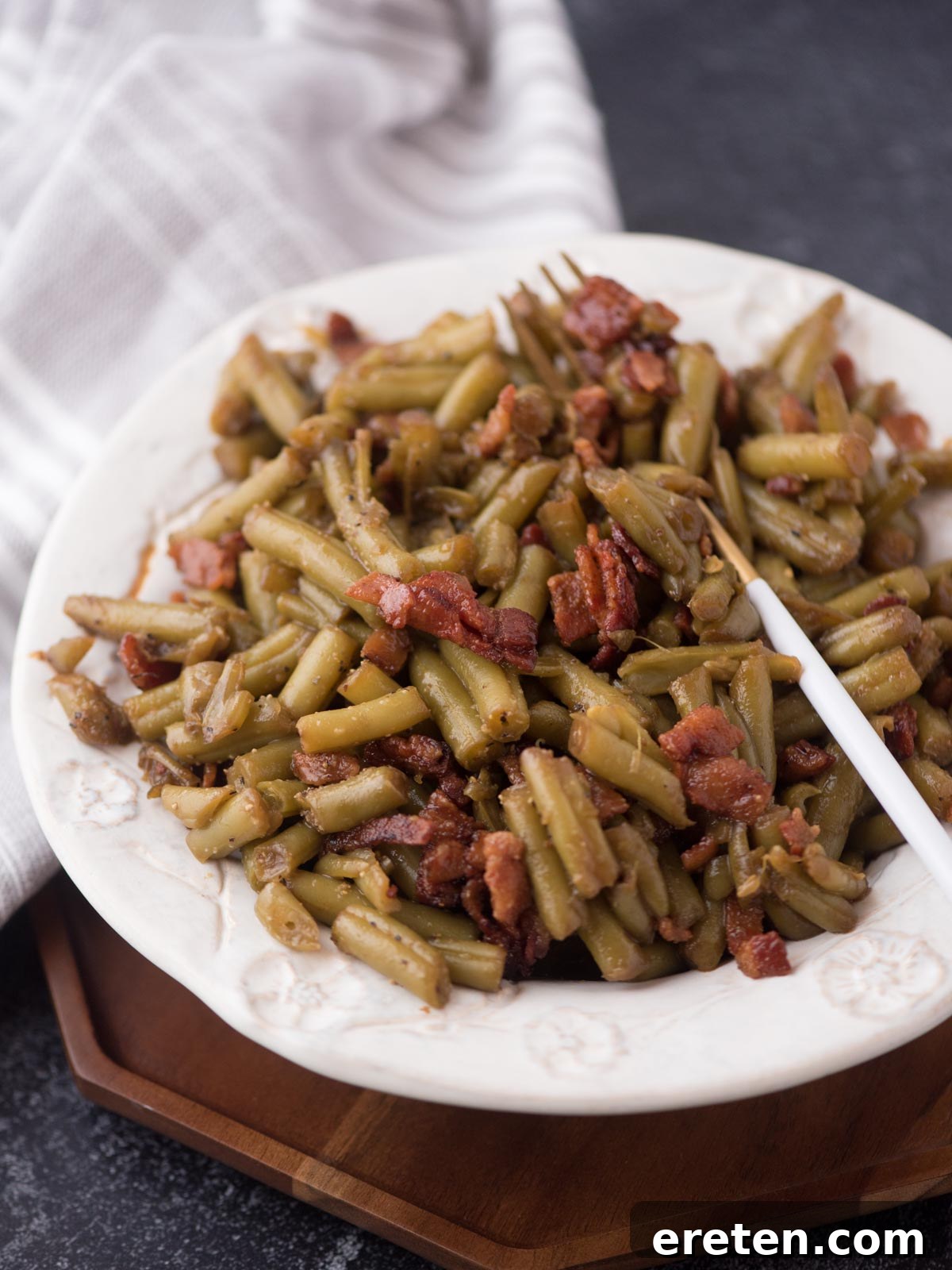 A close-up shot of the finished crack green beans with crispy bacon bits, showcasing their appealing glaze and texture.