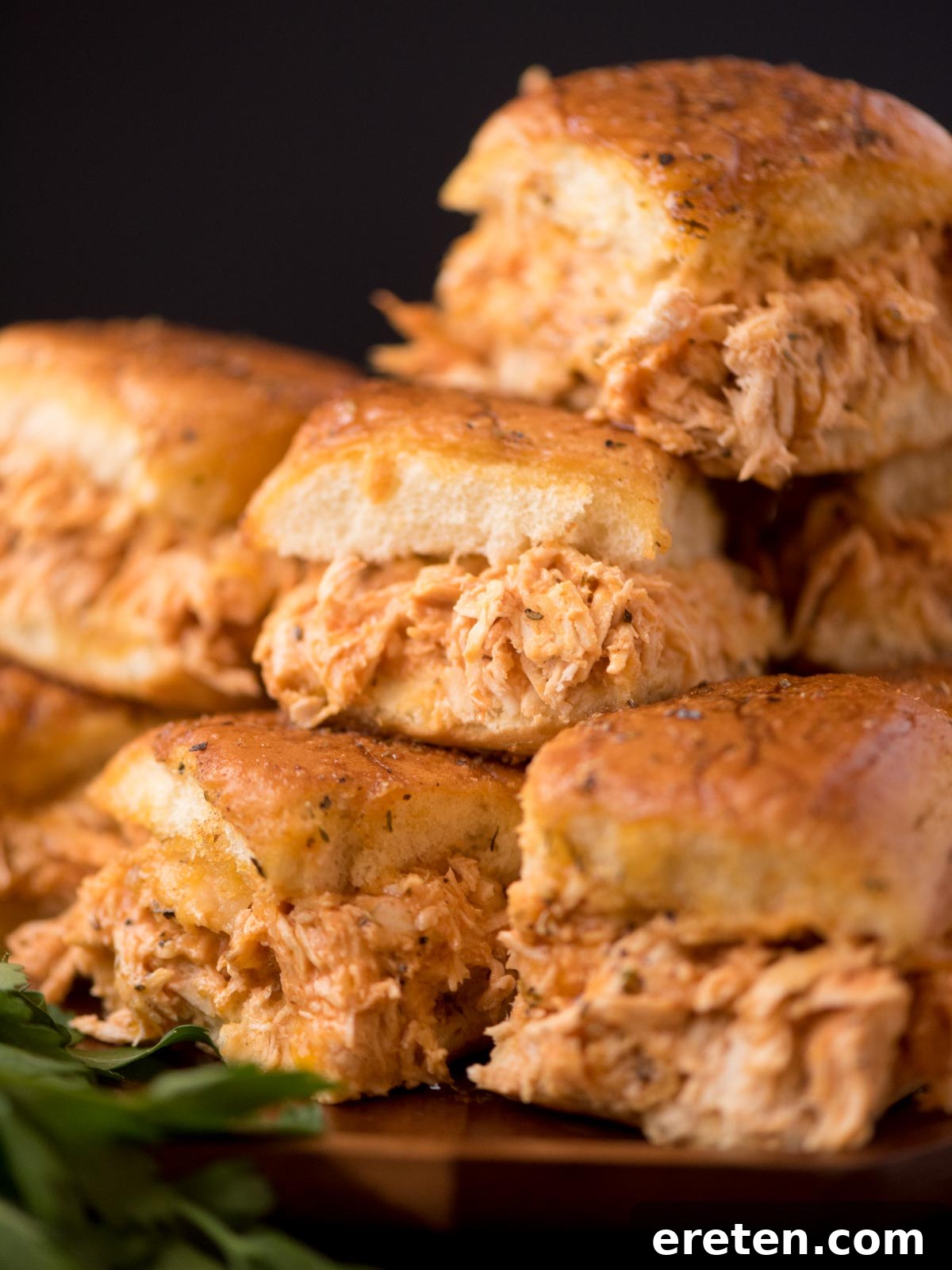 Buffalo chicken sliders stacked on top of one another on a plate.
