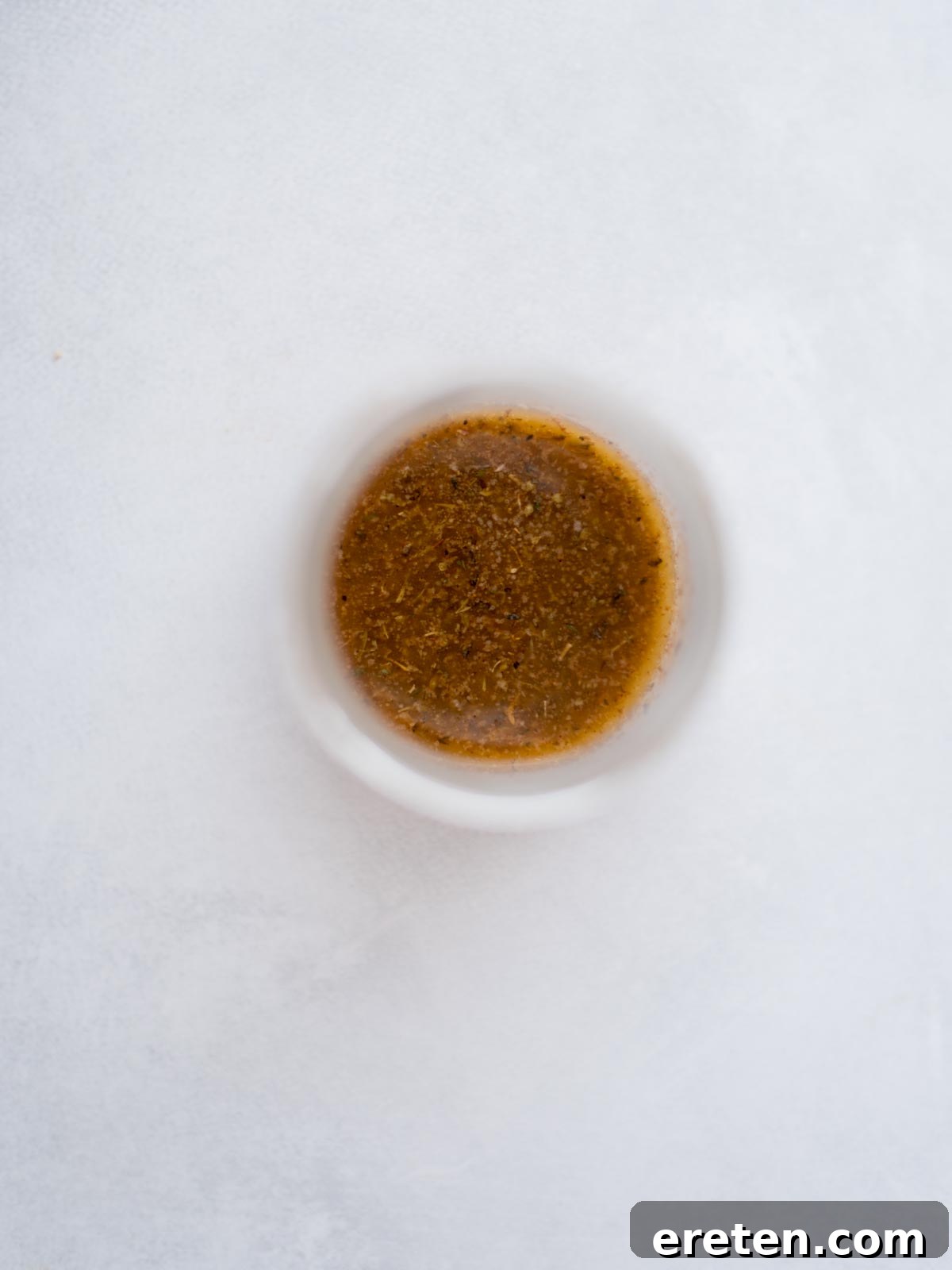 Seasoned melted butter in a small bowl for buffalo chicken sliders.