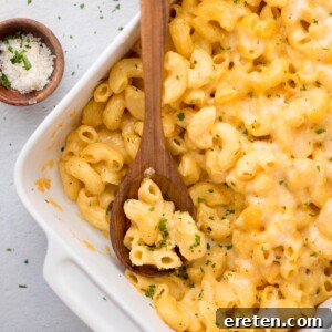 Scoop of mac and cheese taken out of a baking dish with a wooden spoon resting in it, highlighting its creamy, inviting texture.