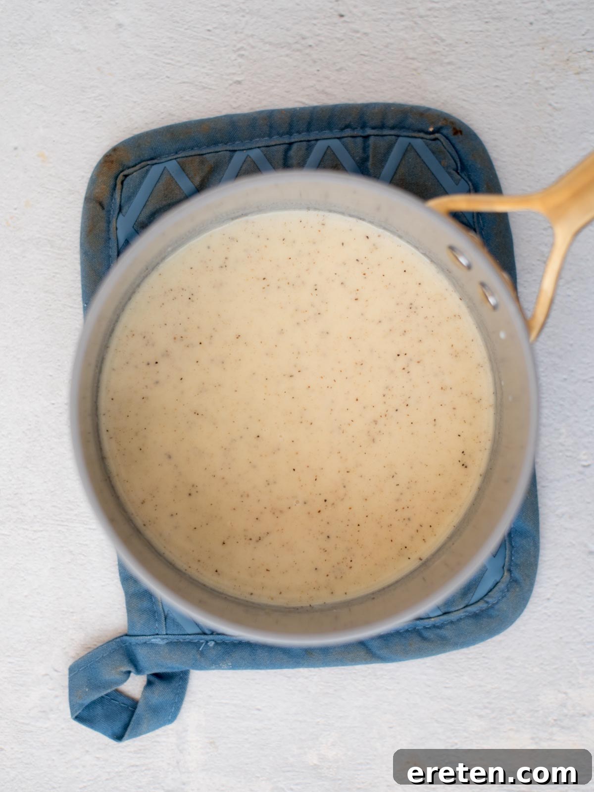 A golden-brown roux simmering gently in a saucepan, forming the essential base for the creamy cheese sauce.