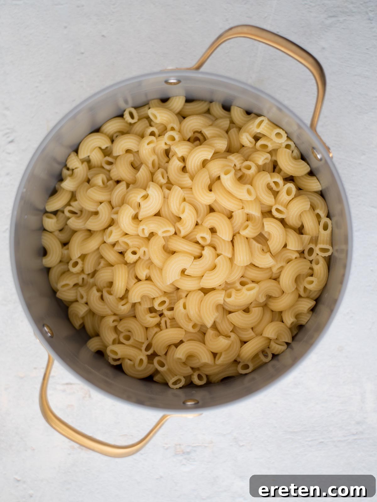 A large pot filled with perfectly cooked elbow macaroni pasta, al dente and drained, awaiting the addition of the rich cheese sauce.