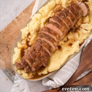 sliced pork tenderloin on top of mashed potatoes in a serving platter