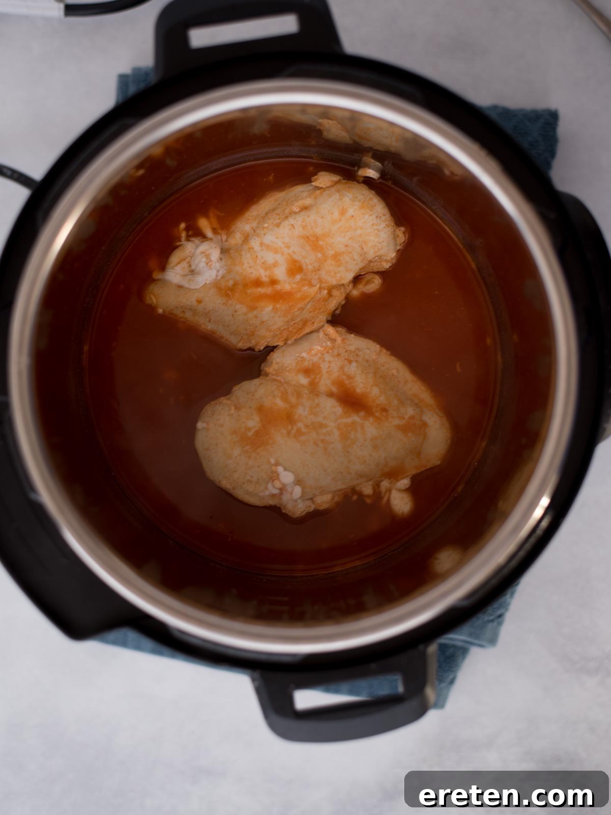 Cooked chicken breasts and buffalo sauce inside the instant pot.