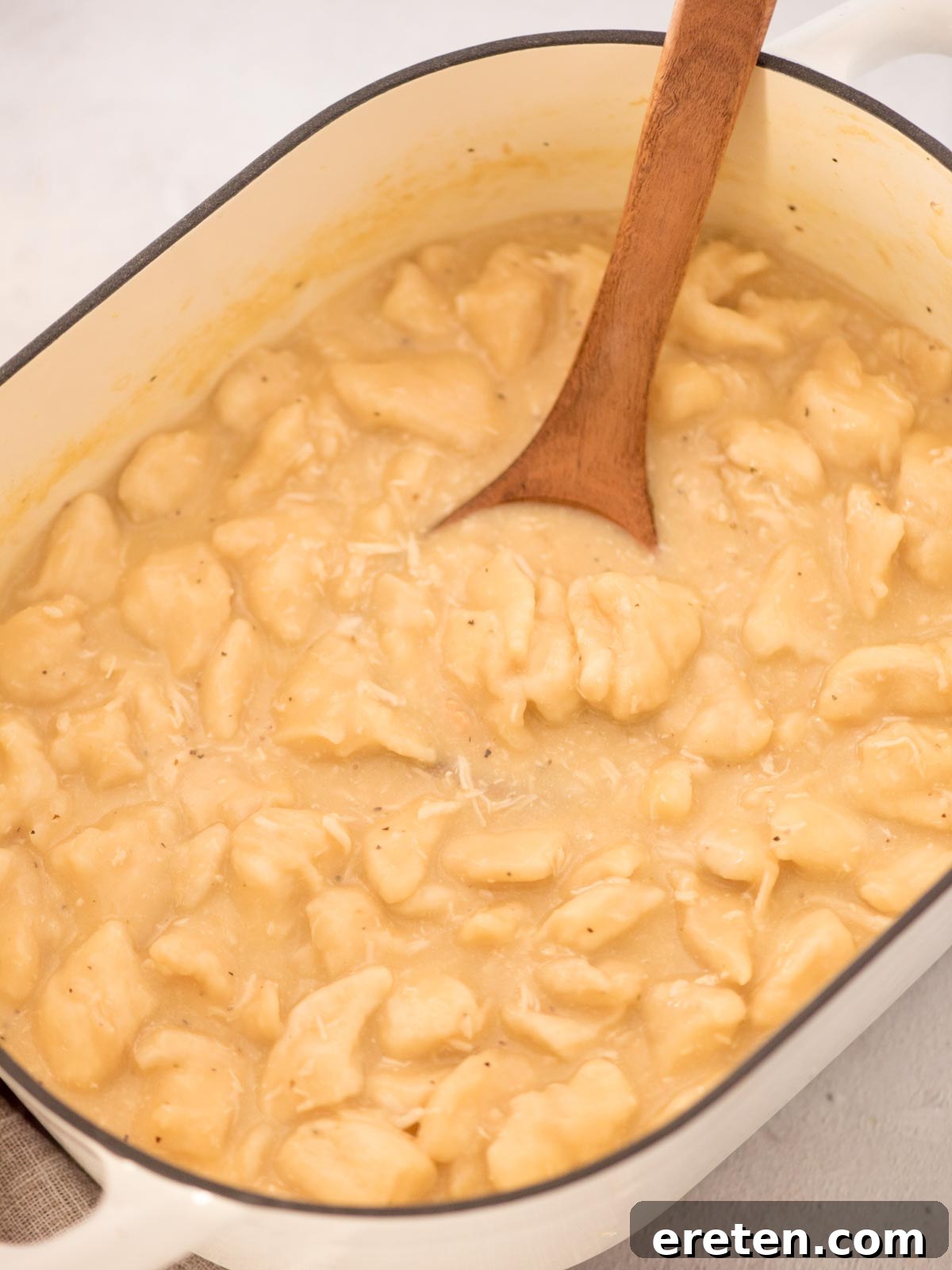 Ready to serve chicken and dumplings with canned biscuits with a serving spoon tucked in it.