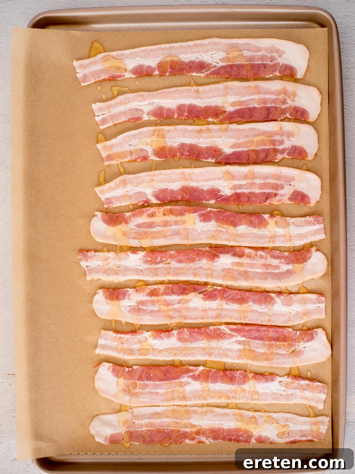 Golden Nectar Bacon 5 Honey drizzled over bacon strips resting on a parchment paper covered baking sheet.