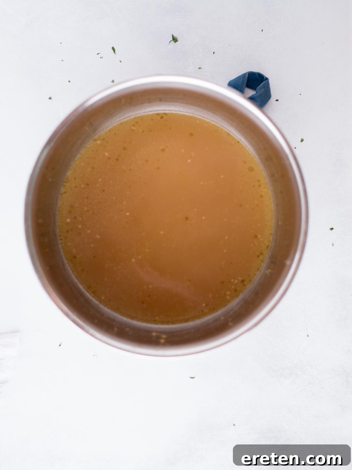 The Ultimate Homemade Chicken Broth 9 Freshly strained chicken broth, clear and golden, resting in a large mixing bowl after separating from the solids.