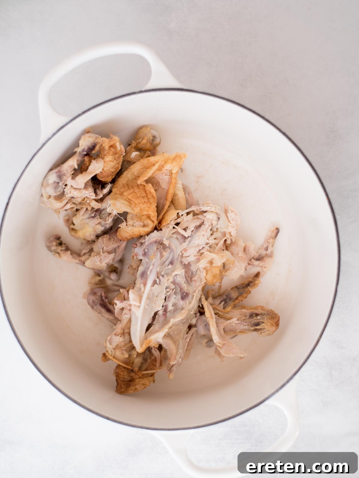 The Ultimate Homemade Chicken Broth 4 Rotisserie chicken scraps and bones placed in a Dutch oven, ready for broth making.