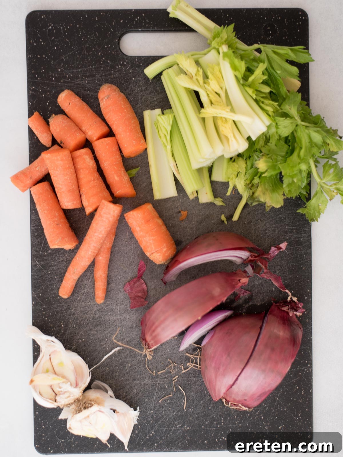 The Ultimate Homemade Chicken Broth 5 Chopped celery, carrots, garlic, and onion neatly arranged on a cutting board, prepared for the broth.