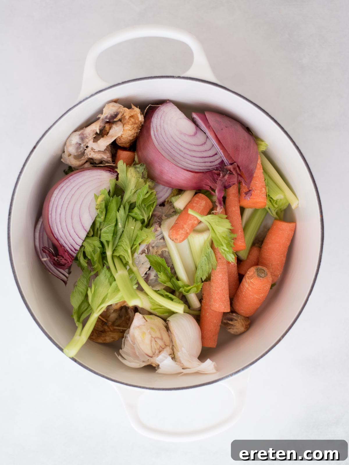 The Ultimate Homemade Chicken Broth 6 A Dutch oven filled with chicken scraps and chopped vegetables, including celery, carrots, garlic, and onion, before adding water.