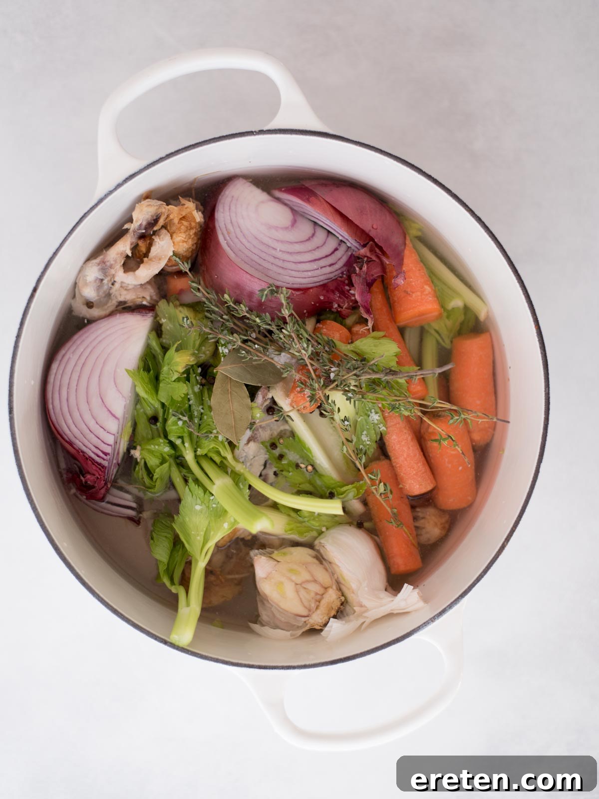 The Ultimate Homemade Chicken Broth 7 Chicken scraps, vegetables, and herbs submerged in water within a Dutch oven, ready for simmering.
