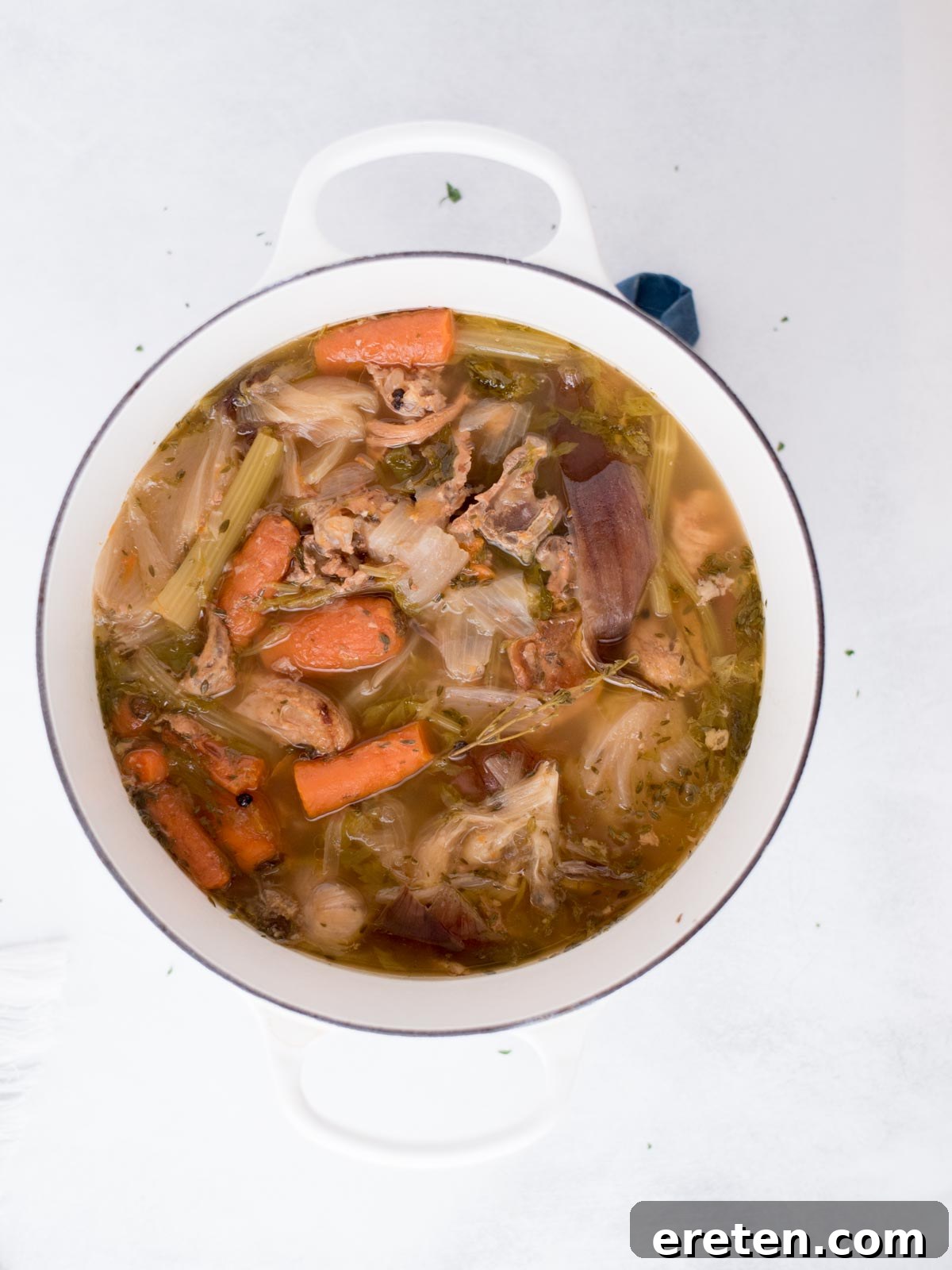 The Ultimate Homemade Chicken Broth 8 Unstrained chicken broth, still containing all the cooked ingredients, gently simmering in a Dutch oven.