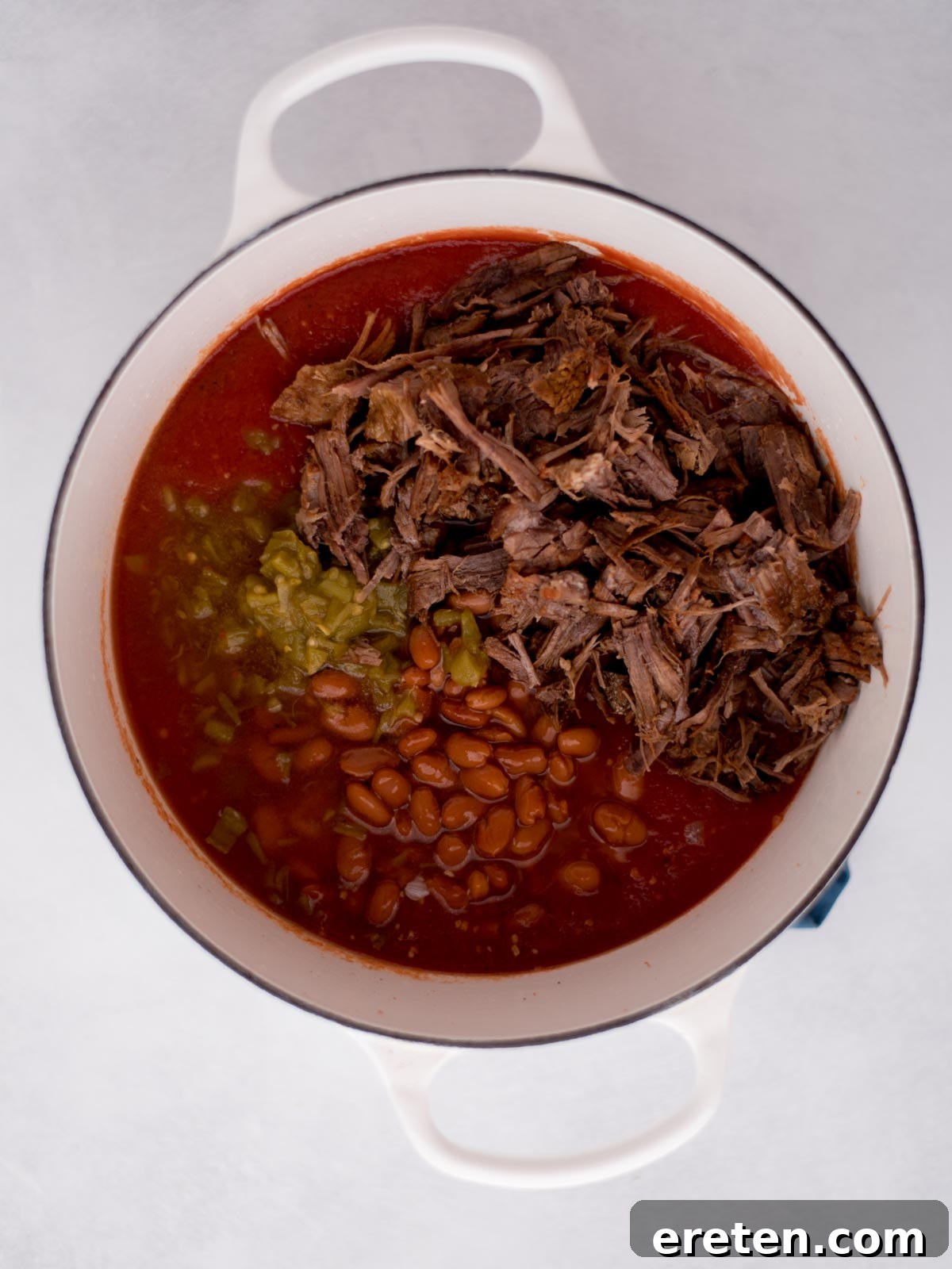 ingredients for brisket chili added into a dutch oven before they've been mixed together