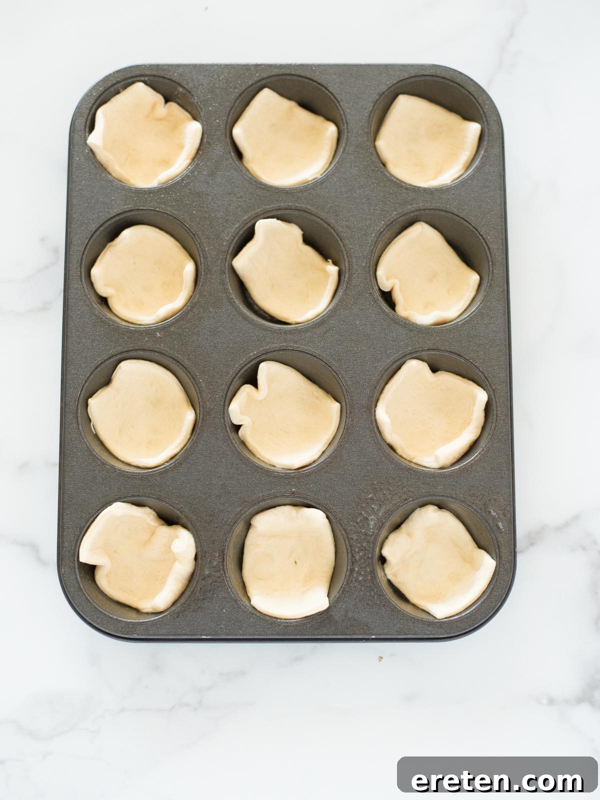 Touchdown BBQ Meatball Crescents 4 Crescent roll dough squares neatly placed in a muffin tin, ready for assembly.