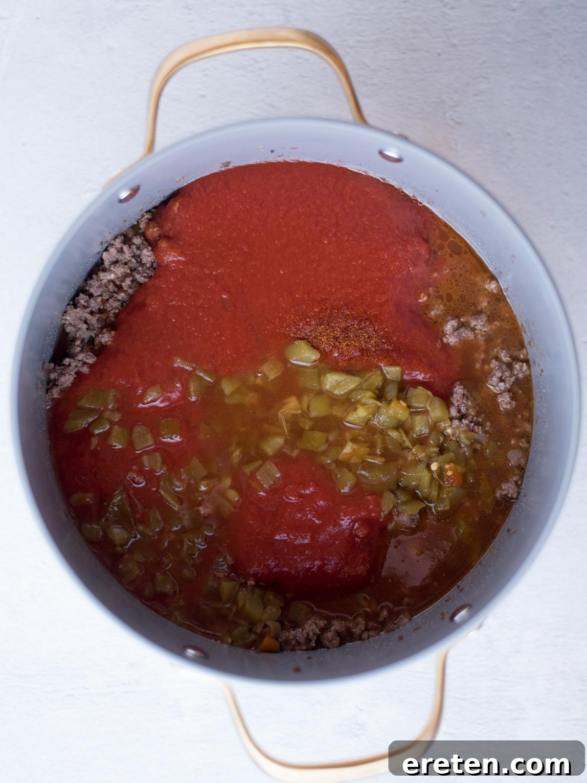 cooked ground beef along with tomato sauce, green chiles, and water in a stock pot