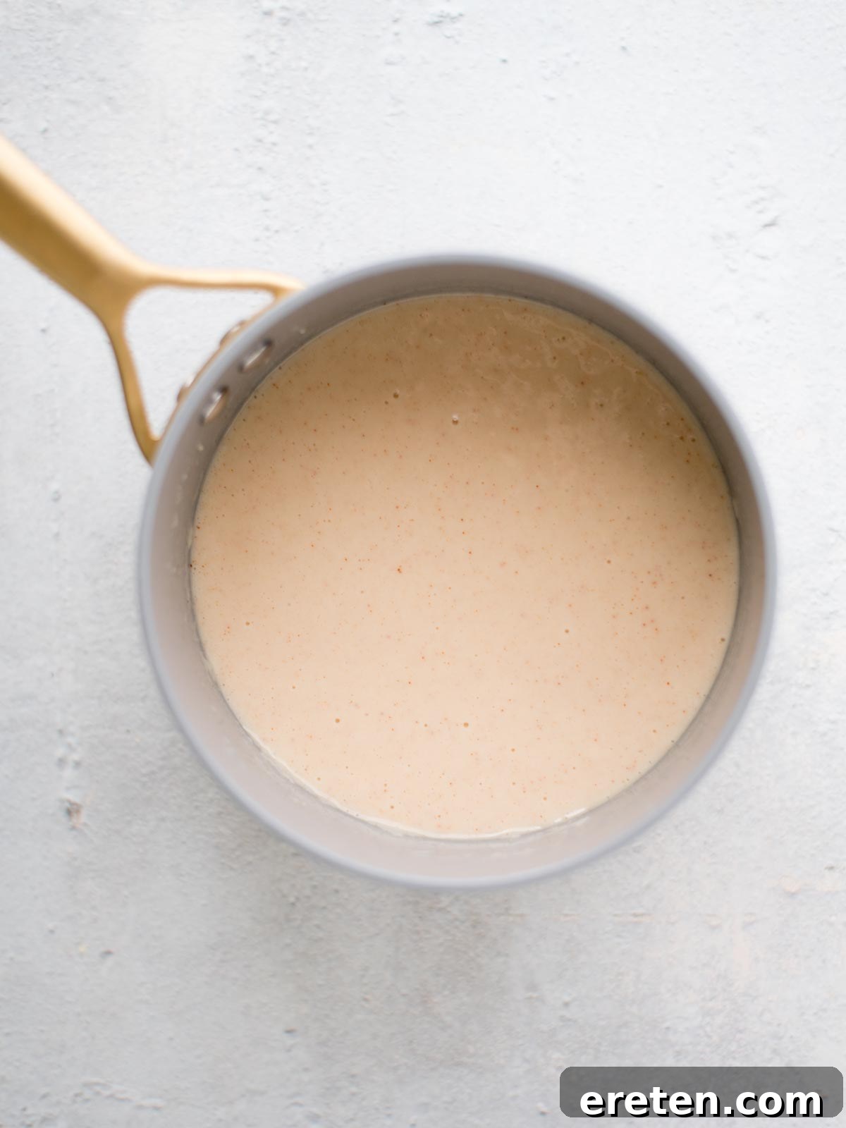The simmering, seasoned milk and roux mixture in a saucepan, thickened to a smooth consistency before the cheese is added.