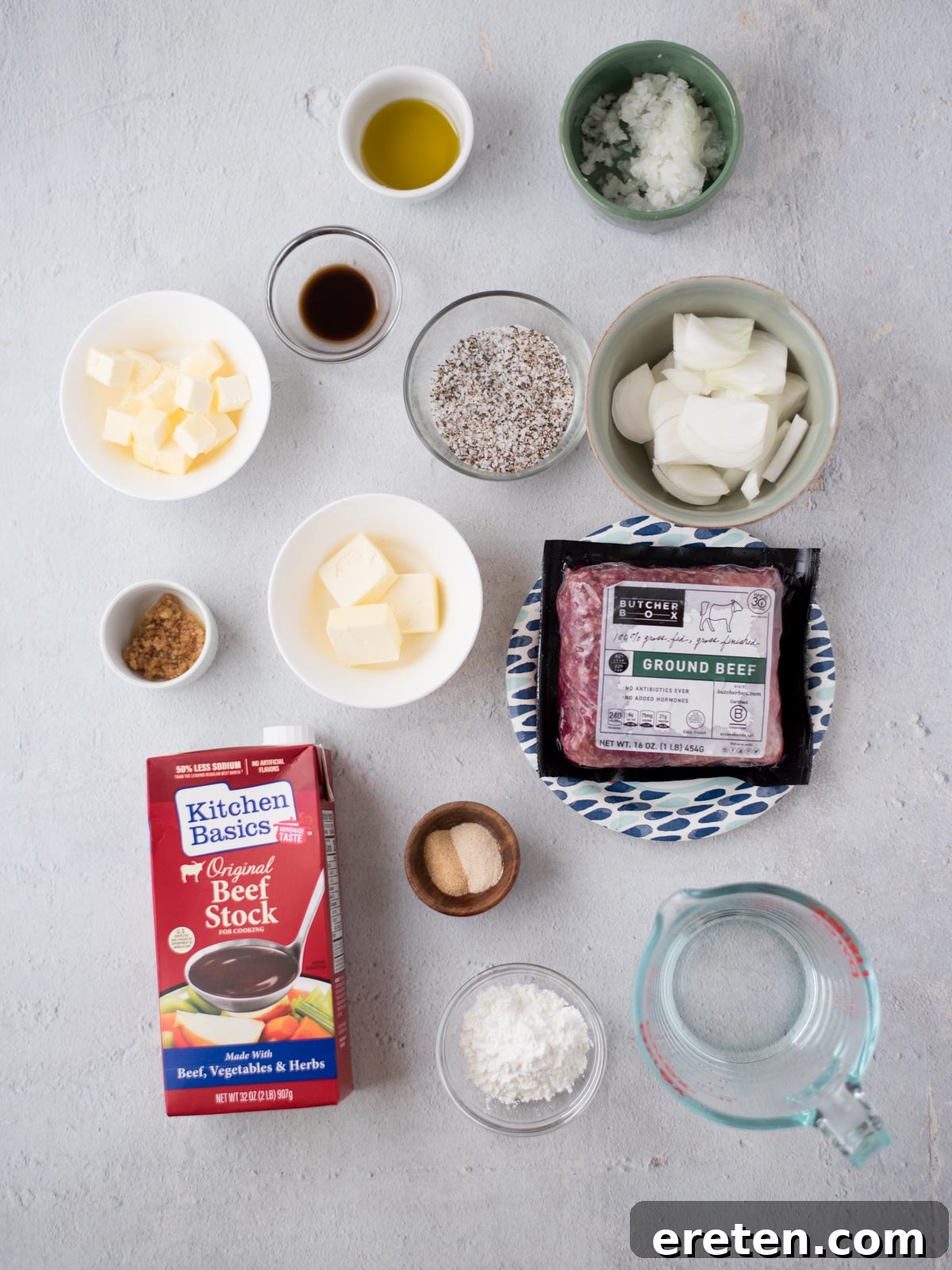 Gravy Smothered Hamburger Steak 3 A collection of fresh and pantry ingredients laid out for making hamburger steak with gravy, including ground beef, onions, garlic, butter, olive oil, beef stock, and various seasonings.