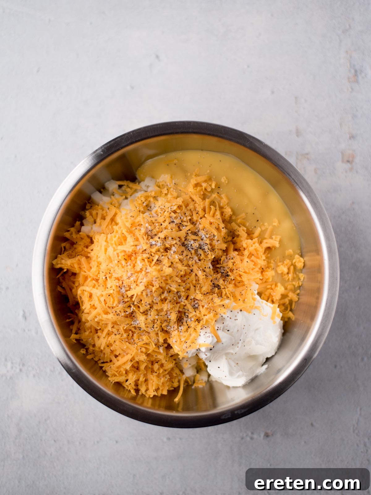 Close-up of creamy, cheesy funeral potato filling in a large mixing bowl, showing the texture before baking.