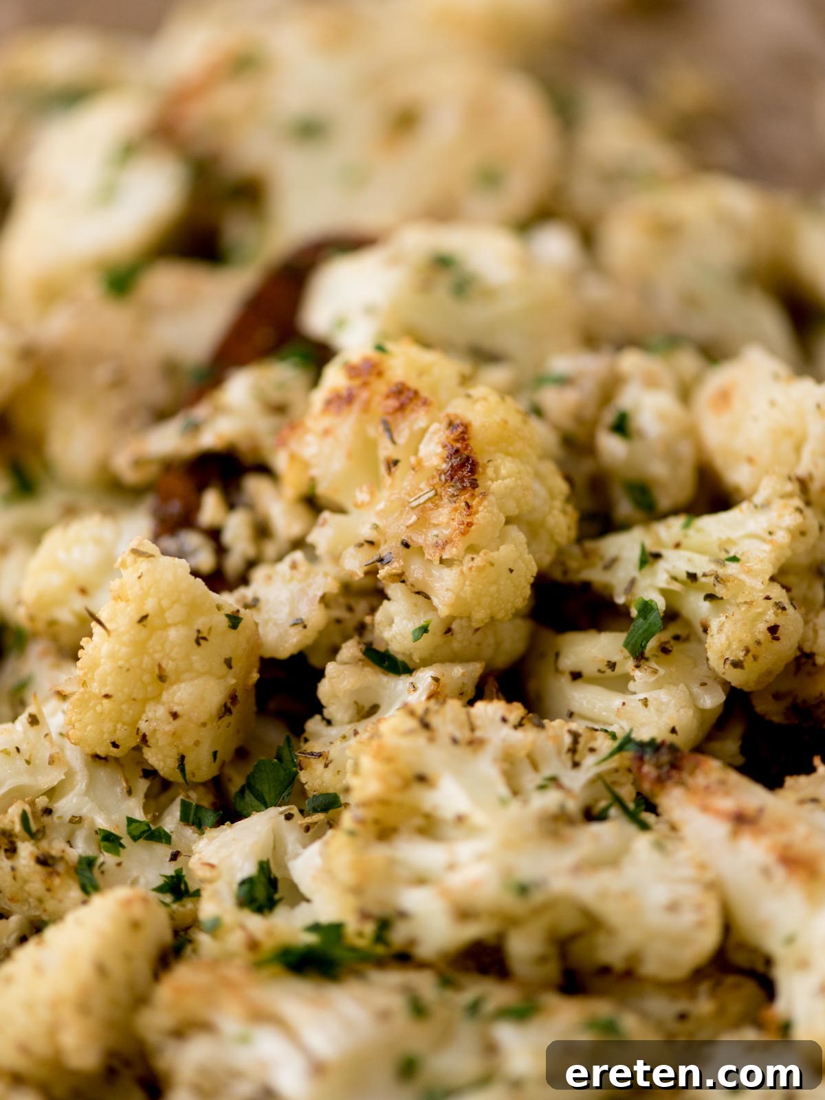 roasted cauliflower being scooped from a baking sheet after cooking