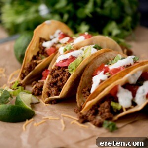 ground beef tacos on parchment paper surrounded by cilantro and limes