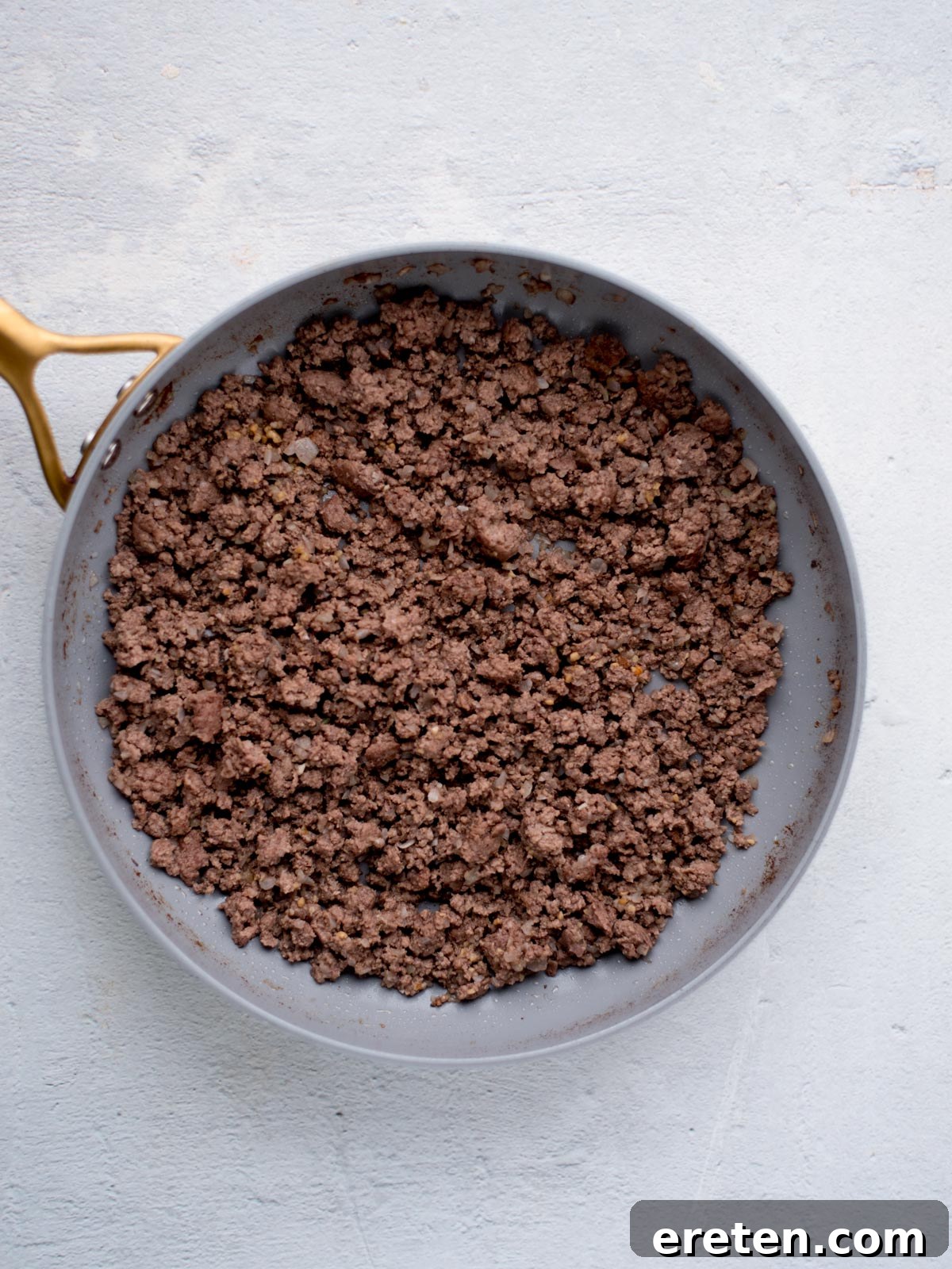 Close-up of perfectly cooked ground beef in a skillet, ready for seasoning.