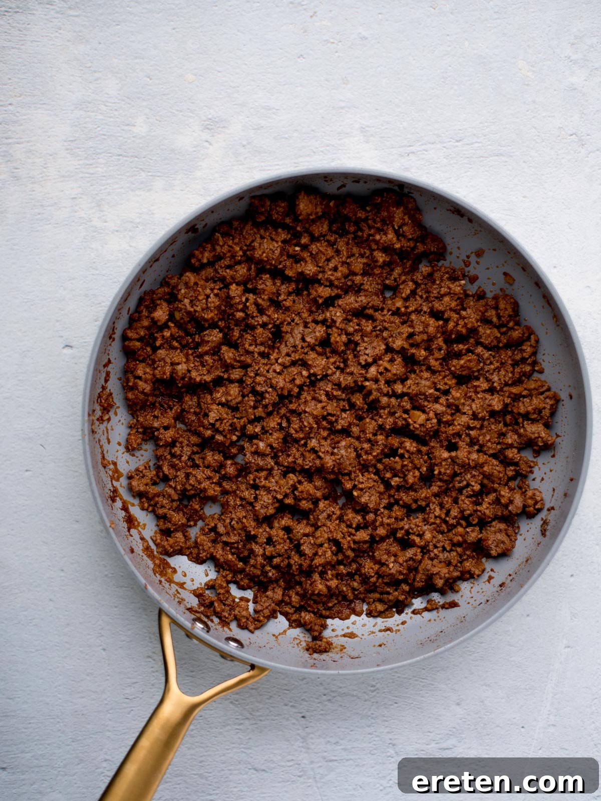 Seasoned ground beef for tacos simmering in a skillet with tomato sauce, creating a rich and saucy filling.