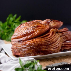 brown sugar glazed ham on a plate surrounded by a kitchen towel and parsley