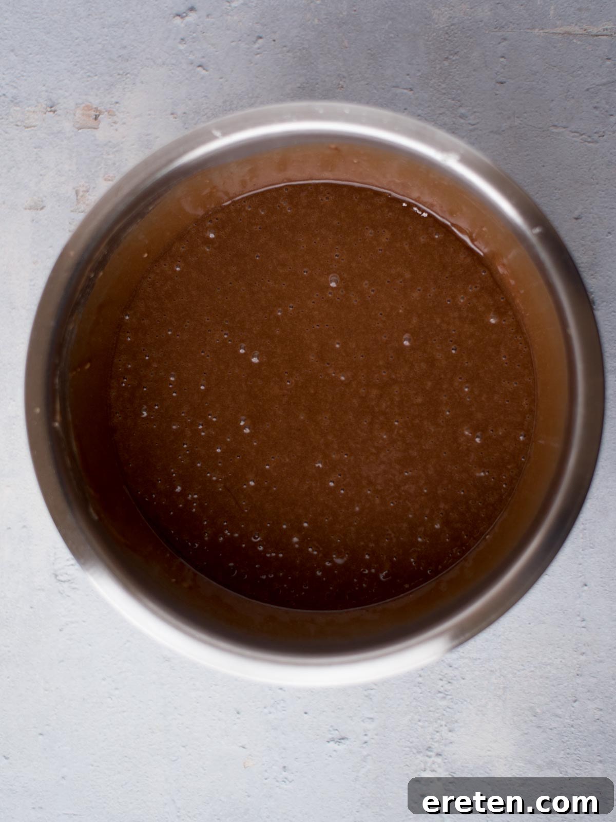 All Texas Sheet Cake ingredients, including the chocolate mixture, fully combined in a mixing bowl, resulting in a dark, smooth, pourable batter.
