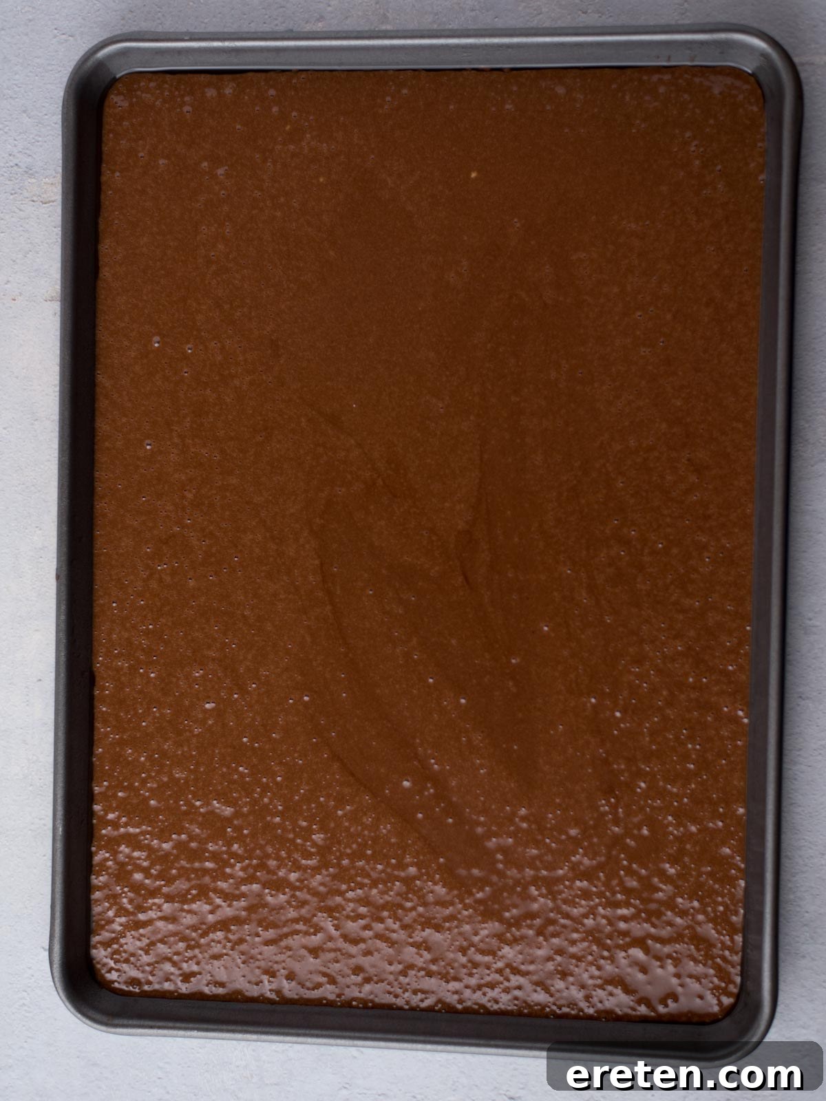 The unbaked Texas Sheet Cake batter, evenly spread in a greased baking sheet, ready to be placed into the oven.