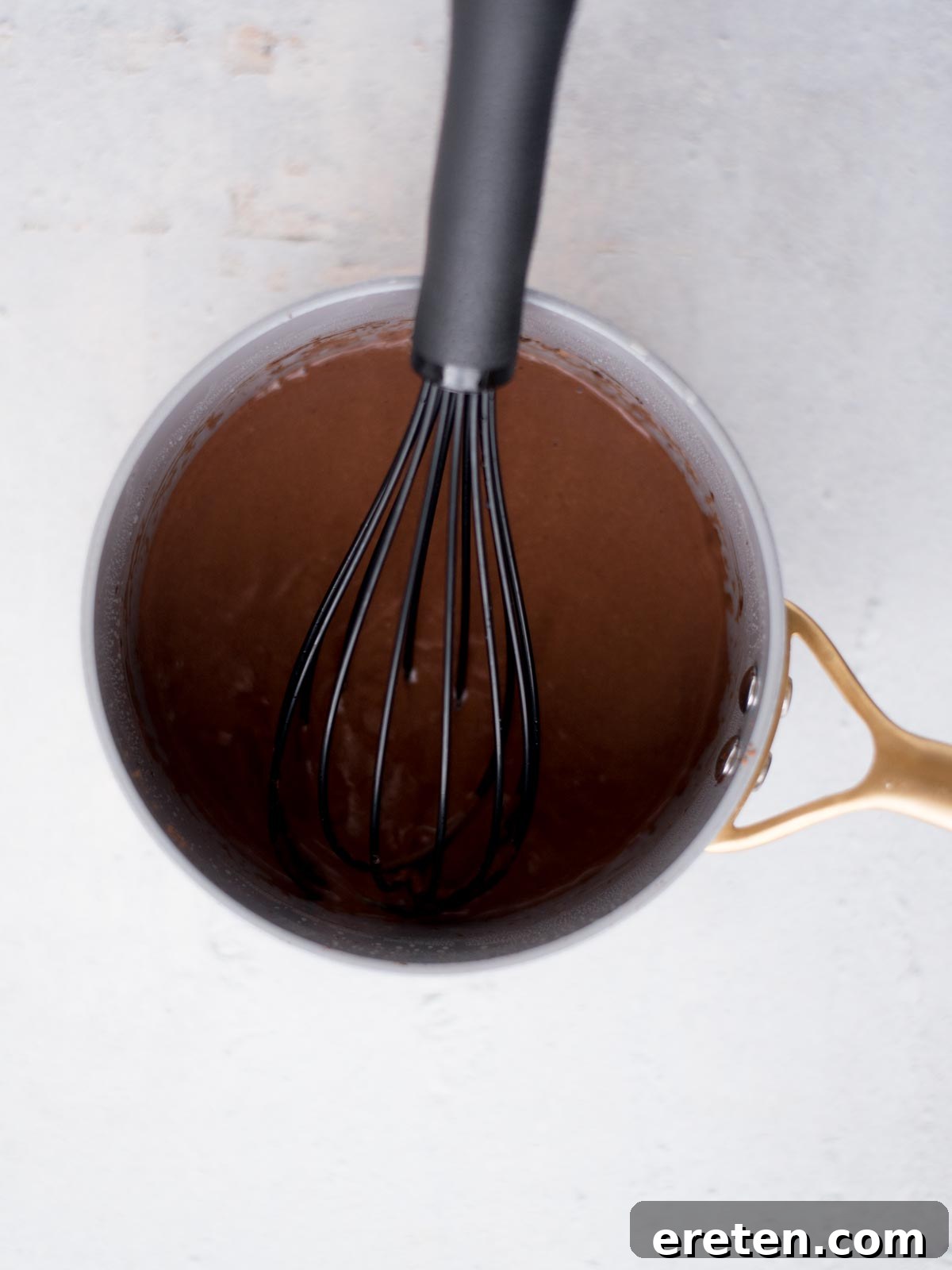 Chocolate and buttermilk mixture for Texas Sheet Cake frosting being heated in a saucepan, showcasing its smooth, rich brown color.