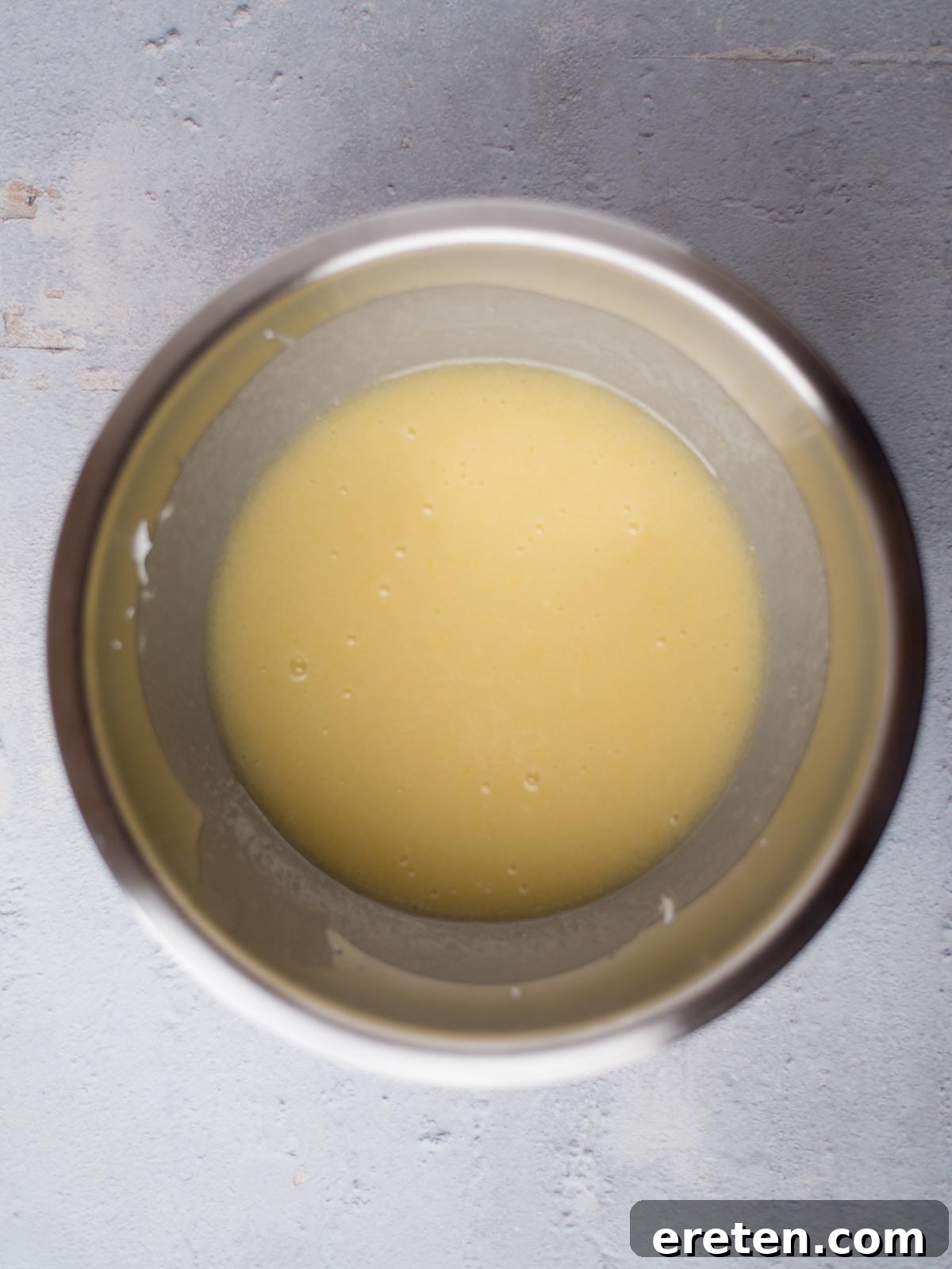 Wet ingredients for Texas Sheet Cake, including sugar, sour cream, and eggs, creamed together in a mixing bowl, showing a light and airy consistency.