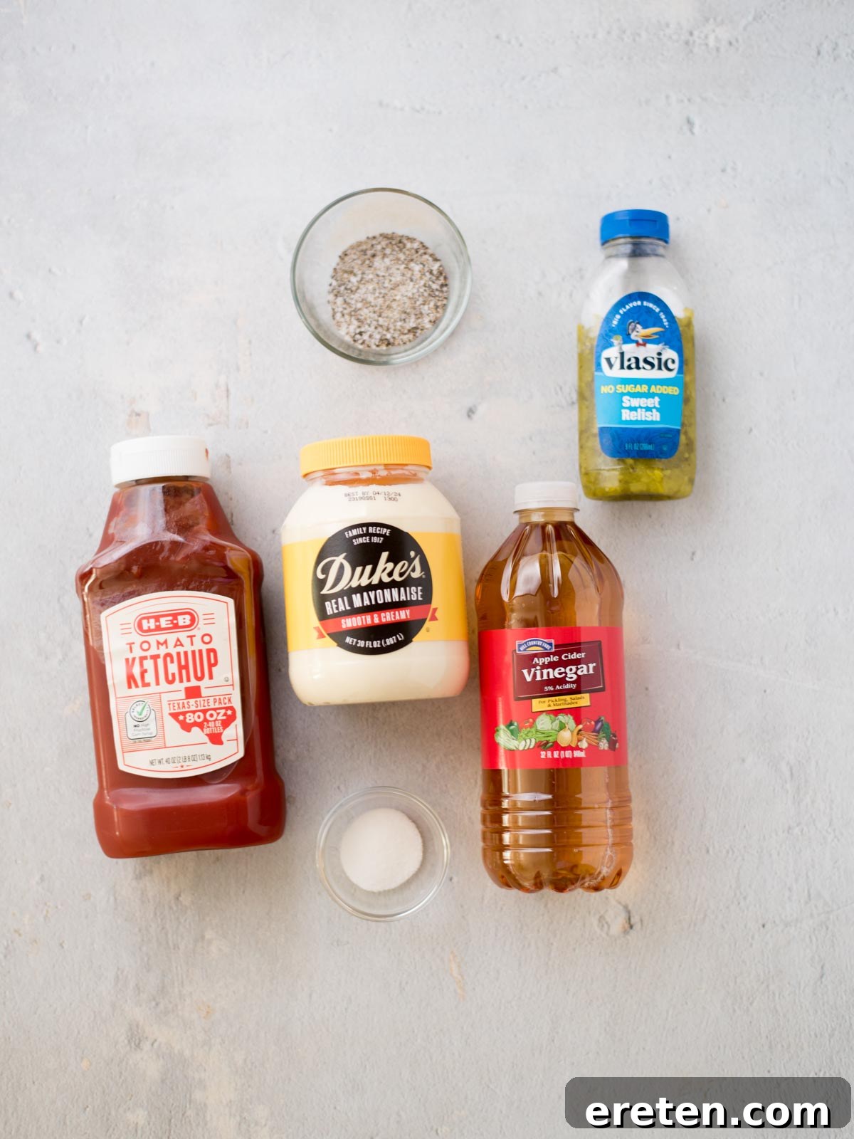 Individual ingredients for making the best burger sauce laid out on a clean surface: mayonnaise, ketchup, sweet pickle relish, sugar, apple cider vinegar, salt, and pepper.