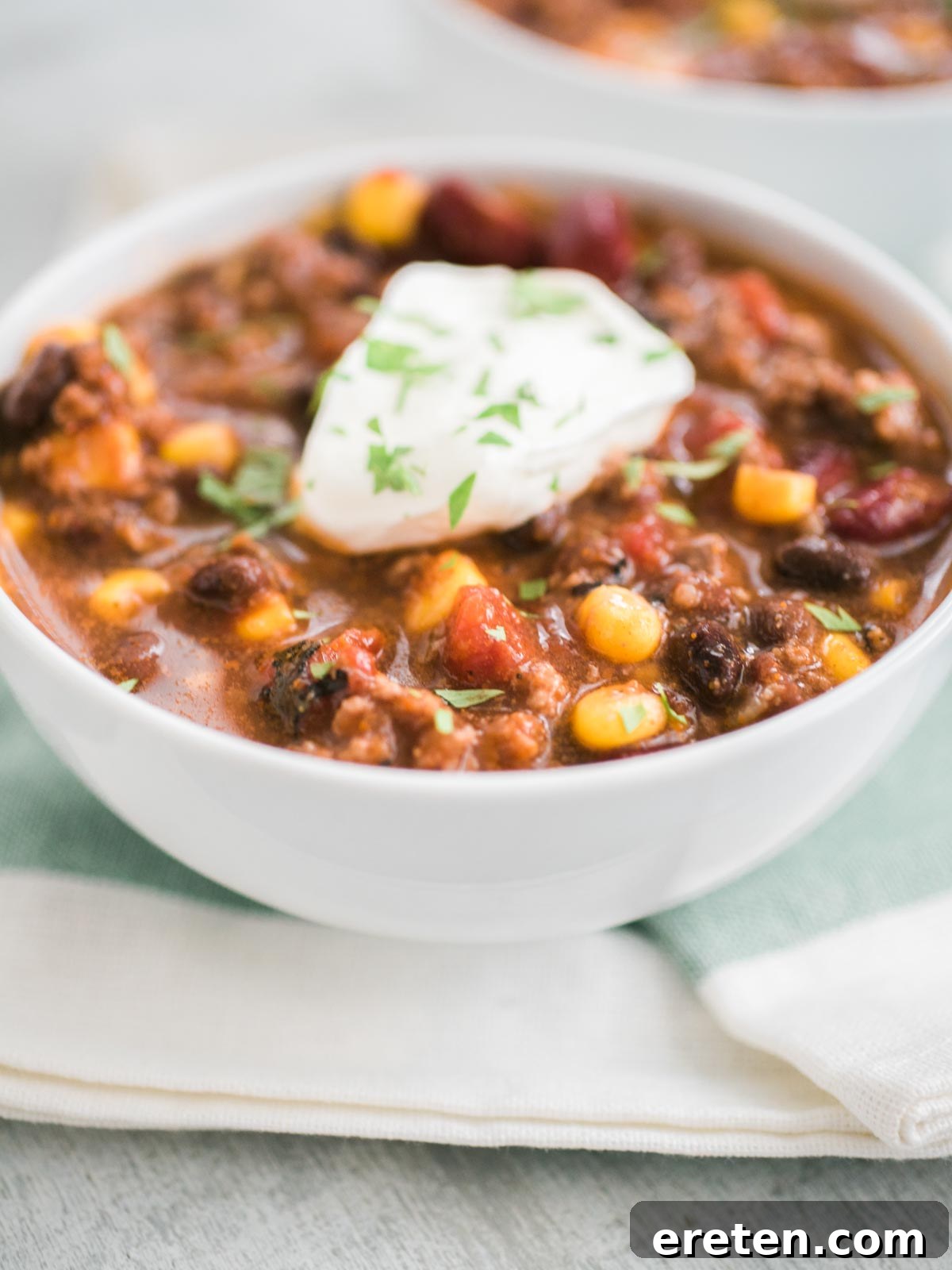 Comforting slow cooker taco soup in a white bowl topped with a dollop of sour cream