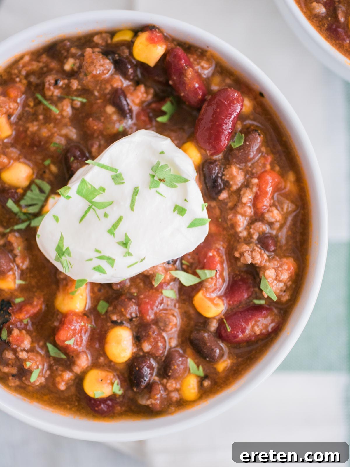 Overhead shot of slow cooker taco soup in a white bowl with sour cream and tortilla strips