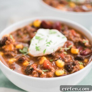 taco soup in a white bowl topped with sour cream