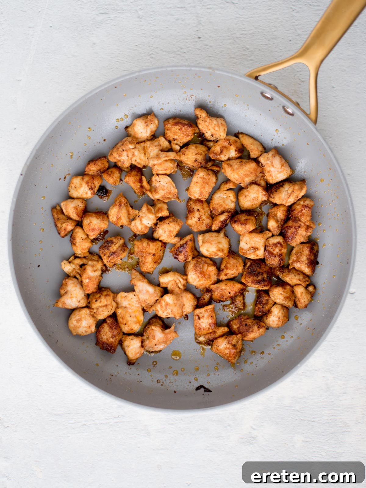 Chicken pieces sauted to a golden brown in a skillet.