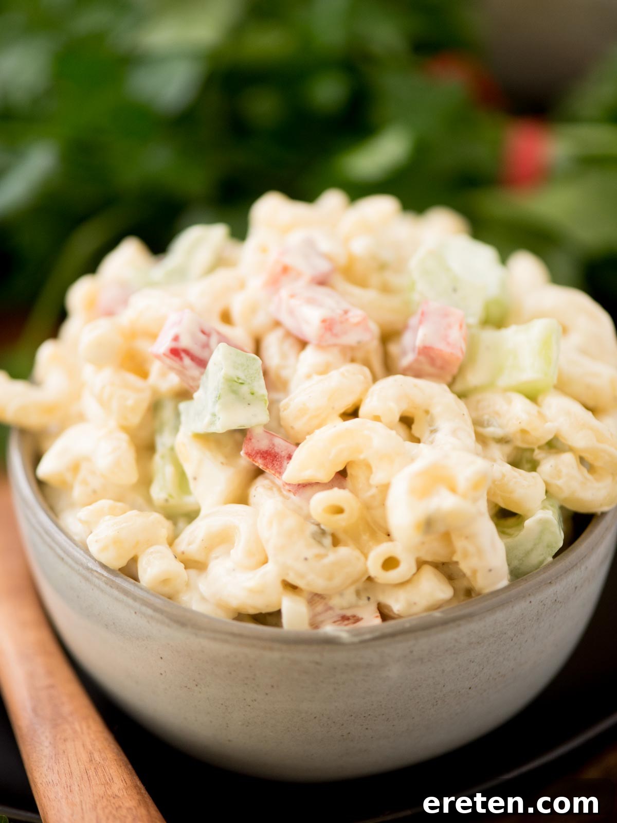 Grandma's Heirloom Macaroni Salad 6 Macaroni salad in a grey bowl surrounded by a serving spoon and fresh parsley.